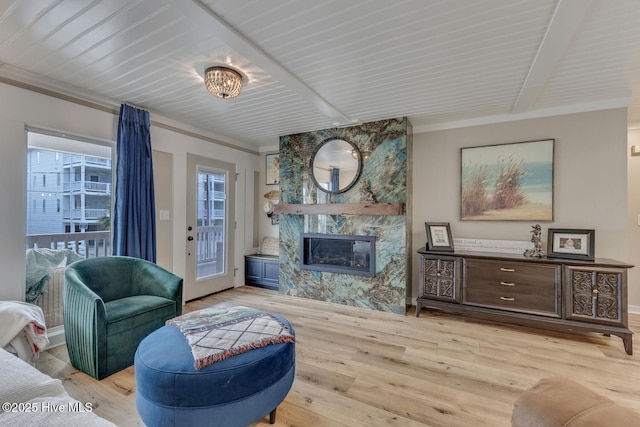 living area featuring a fireplace, light wood-style flooring, ornamental molding, beamed ceiling, and baseboards