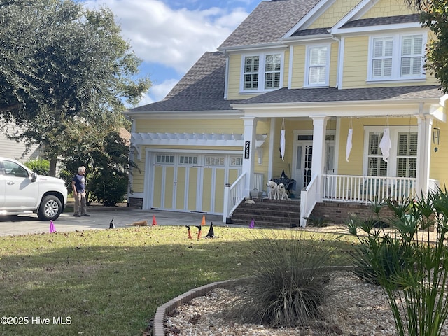 view of front of house with roof with shingles, a porch, an attached garage, driveway, and a front lawn