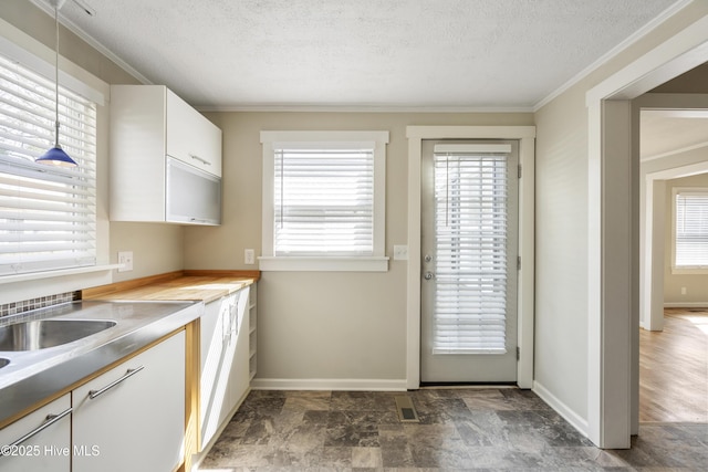 kitchen featuring ornamental molding, light countertops, a textured ceiling, white cabinetry, and pendant lighting