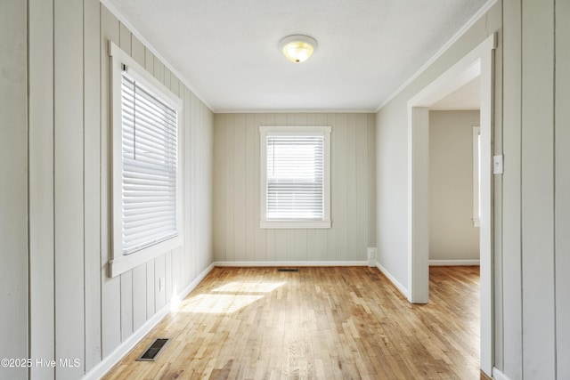 unfurnished room with visible vents, crown molding, baseboards, and wood finished floors