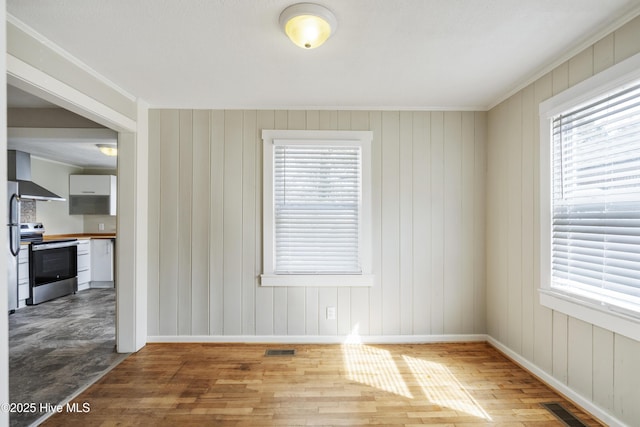 unfurnished room featuring baseboards, visible vents, and wood finished floors