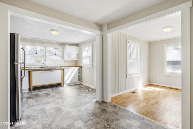 kitchen with baseboards, visible vents, white cabinetry, and freestanding refrigerator