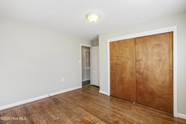 unfurnished bedroom with a closet, baseboards, and wood finished floors