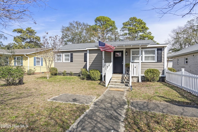 view of front facade with fence, a front lawn, and roof with shingles