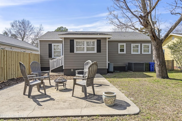 rear view of property with an outdoor fire pit, cooling unit, fence, a lawn, and a patio area