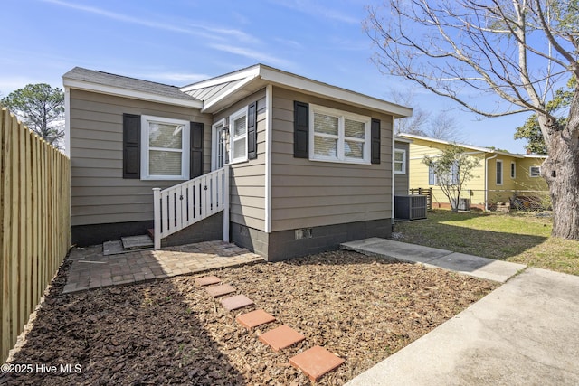 exterior space featuring cooling unit, crawl space, a patio area, fence private yard, and a front lawn