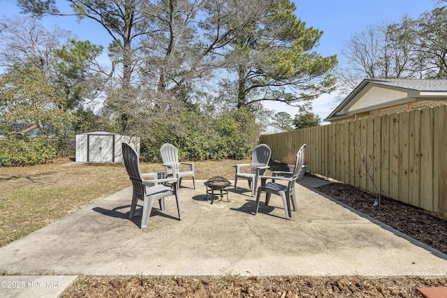 view of patio / terrace featuring a storage shed, an outbuilding, fence, and a fire pit