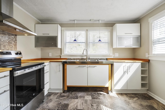 kitchen featuring stainless steel range with electric stovetop, white cabinets, ornamental molding, and wall chimney exhaust hood