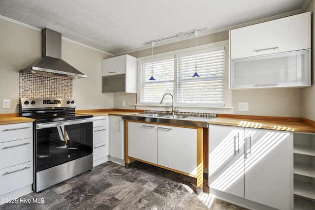 kitchen featuring butcher block countertops, white cabinets, electric stove, ornamental molding, and wall chimney range hood