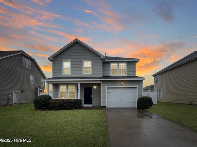 traditional-style house featuring an attached garage, concrete driveway, and a yard