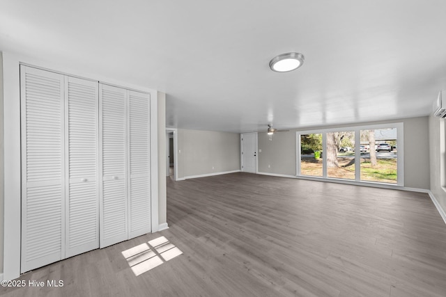 unfurnished living room featuring ceiling fan, wood finished floors, and baseboards