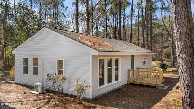 view of side of property featuring a deck, roof with shingles, and ac unit