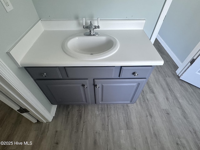 interior details with wood finished floors, a sink, and baseboards