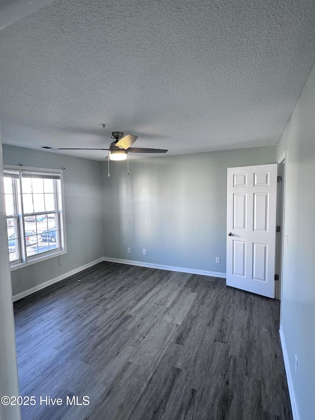 spare room featuring dark wood-style flooring, ceiling fan, a textured ceiling, and baseboards