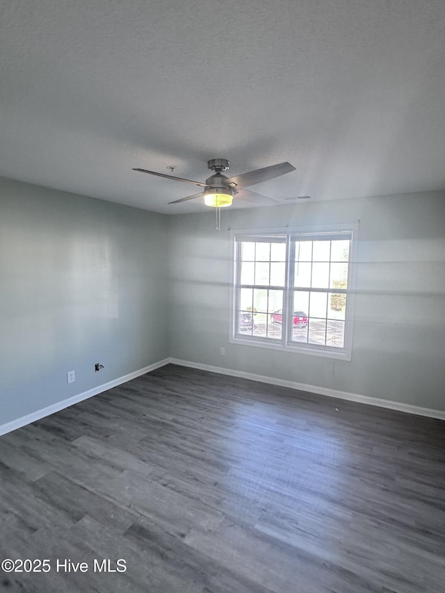 empty room featuring a ceiling fan, dark wood finished floors, a textured ceiling, and baseboards