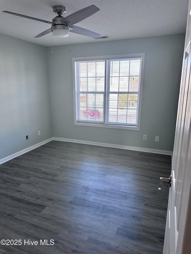 spare room with baseboards, visible vents, and dark wood finished floors