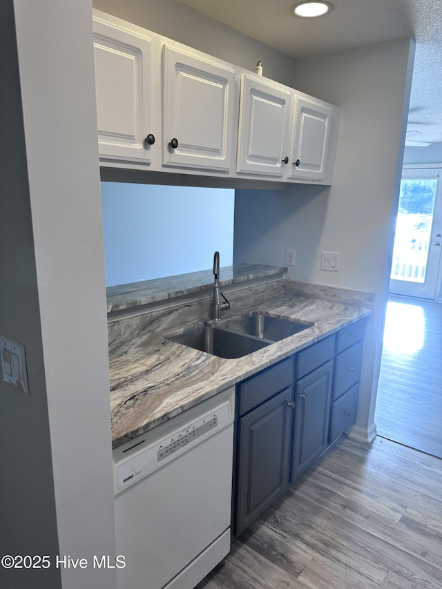 kitchen featuring light wood-style floors, white cabinets, dishwasher, and a sink