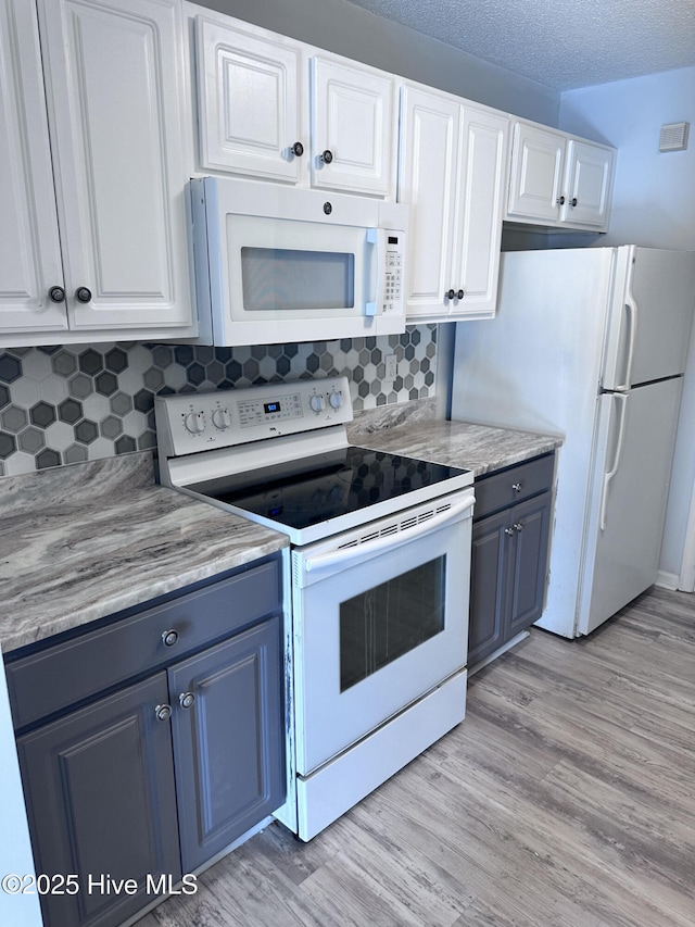 kitchen with tasteful backsplash, white appliances, light wood-type flooring, and white cabinets