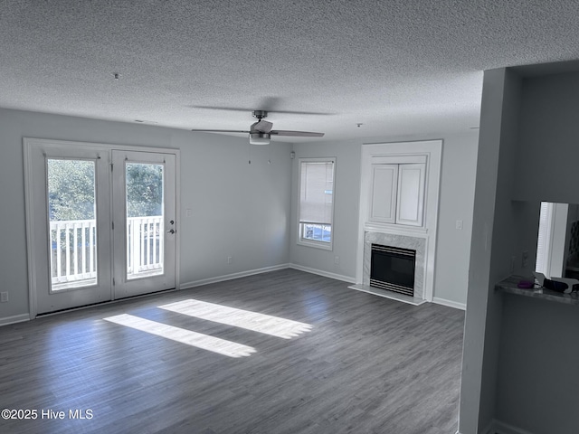 unfurnished living room with a fireplace, a textured ceiling, baseboards, and wood finished floors