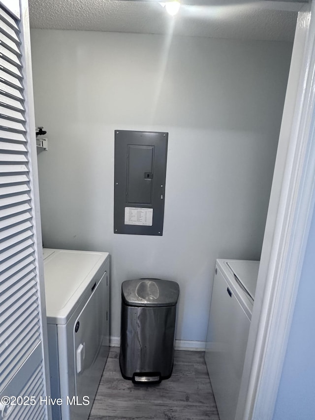 laundry room featuring dark wood-style flooring, washer and clothes dryer, a textured ceiling, laundry area, and electric panel