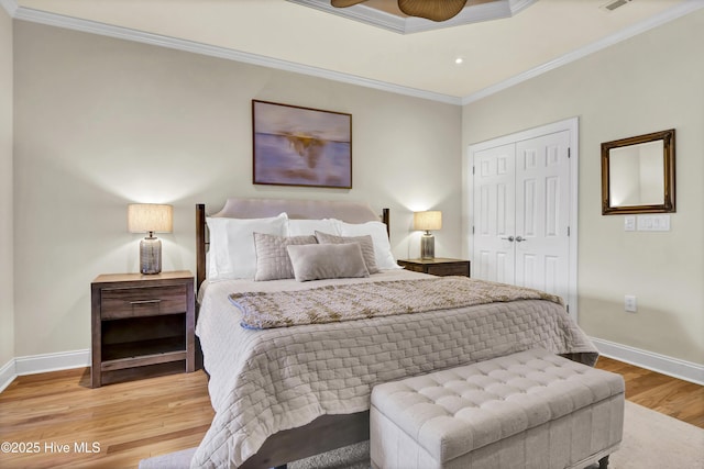 bedroom featuring ornamental molding, a closet, light wood-style floors, and baseboards