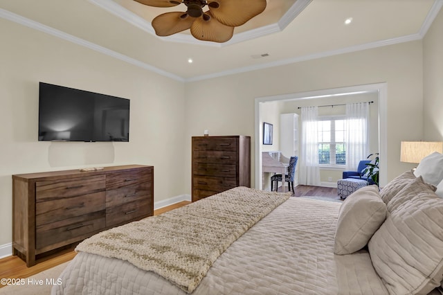 bedroom featuring light wood-type flooring, a tray ceiling, and crown molding