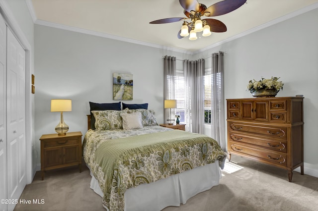 carpeted bedroom with ceiling fan, ornamental molding, a closet, and baseboards