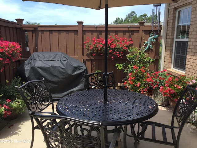 view of patio featuring outdoor dining space, a grill, and fence