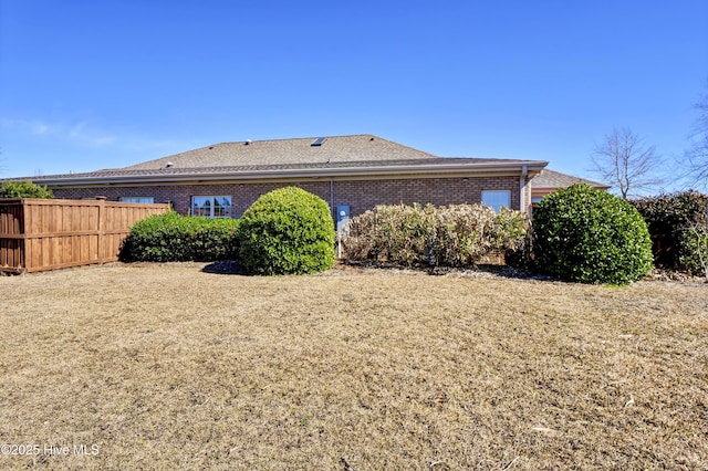 back of house featuring brick siding and fence