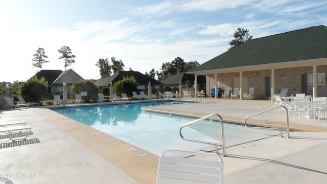 community pool with a patio area and fence