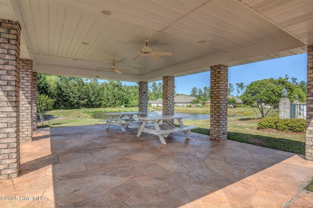 view of patio featuring a ceiling fan, outdoor dining area, and a water view