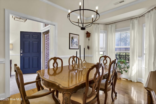 dining area featuring a chandelier, light wood-type flooring, visible vents, and crown molding