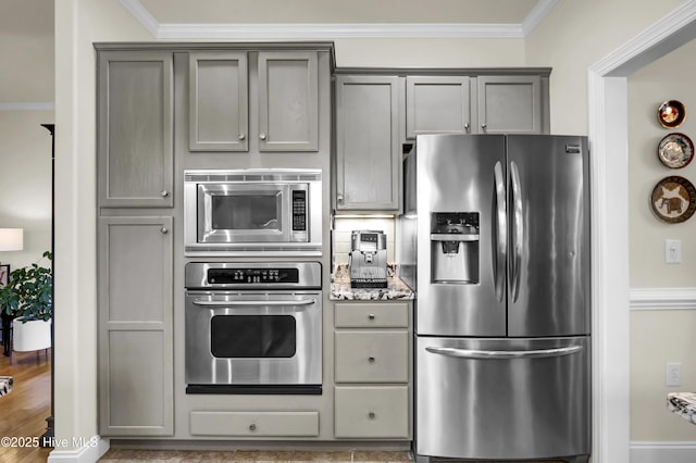 kitchen featuring appliances with stainless steel finishes, gray cabinets, ornamental molding, and tasteful backsplash