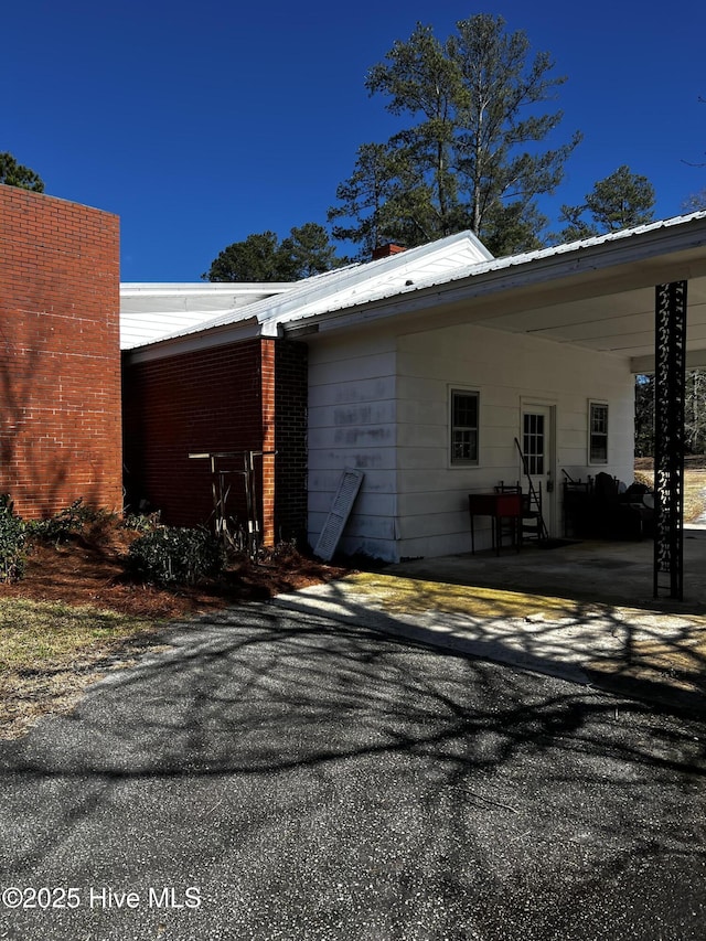 view of property exterior with metal roof, aphalt driveway, and an attached carport