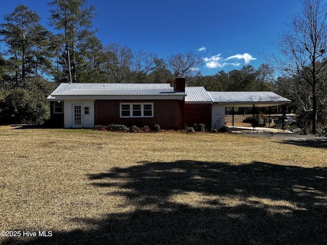 exterior space featuring a carport, a yard, metal roof, and a chimney