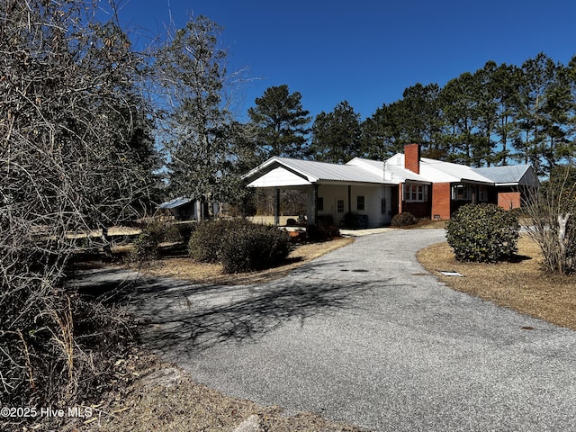 single story home with aphalt driveway and a chimney