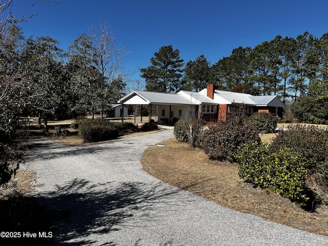 ranch-style house featuring driveway and a chimney