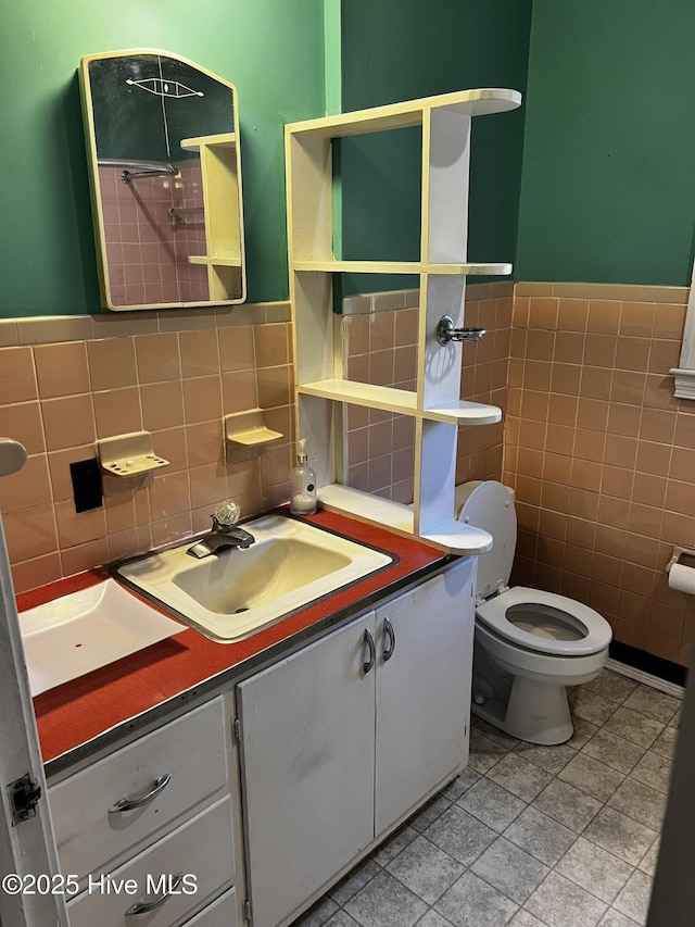 half bathroom featuring tile walls, wainscoting, vanity, and toilet