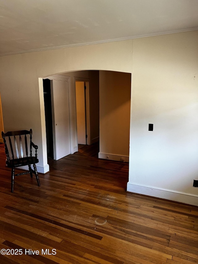 empty room with baseboards, dark wood-type flooring, and crown molding