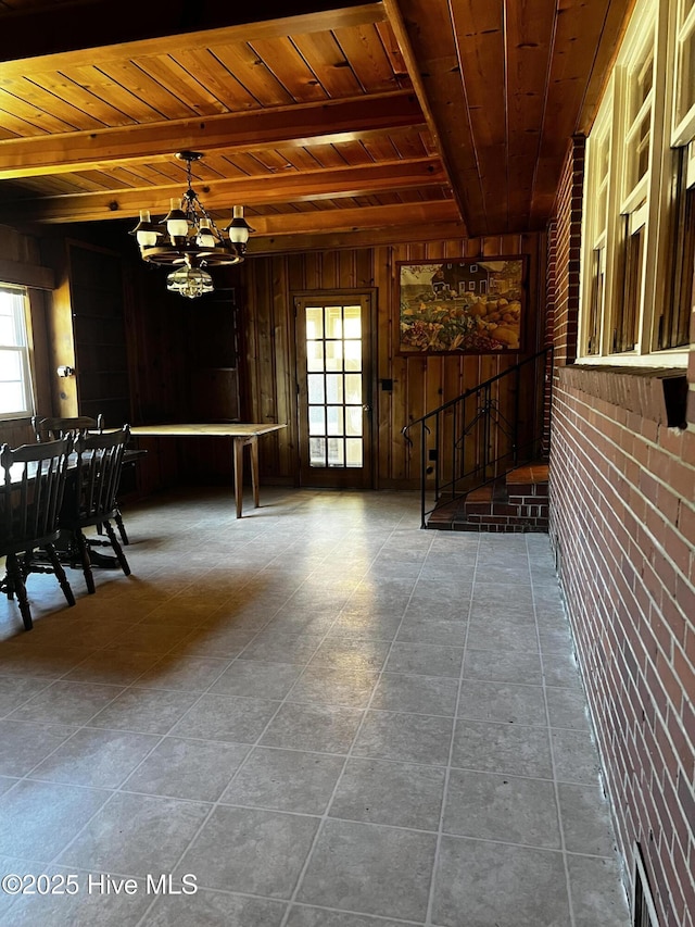 interior space with wooden walls, brick wall, wood ceiling, a chandelier, and beam ceiling