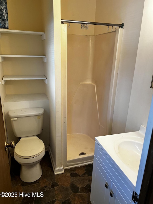 bathroom featuring toilet, a shower stall, stone finish floor, and vanity