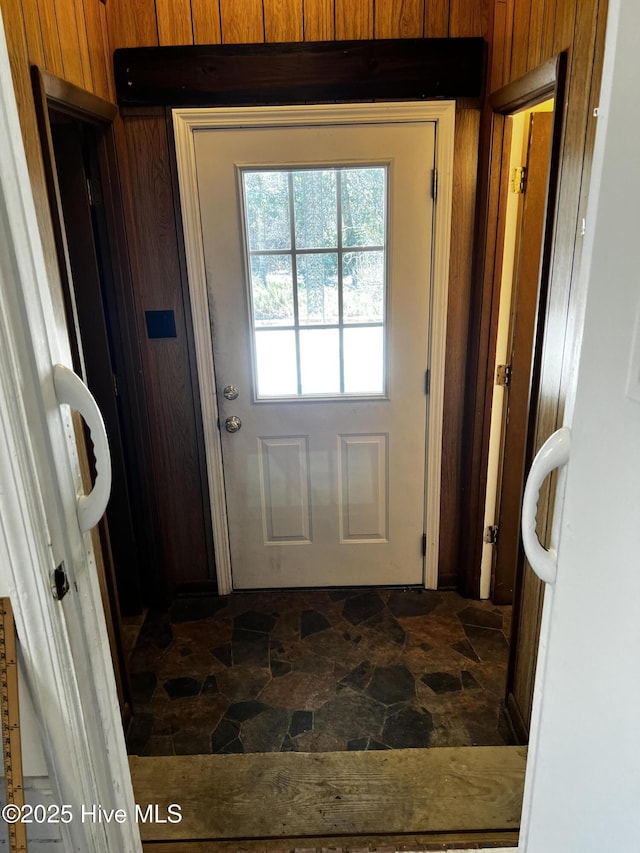 entryway featuring stone finish floor and wooden walls