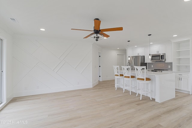 kitchen with an island with sink, white cabinetry, appliances with stainless steel finishes, and light countertops