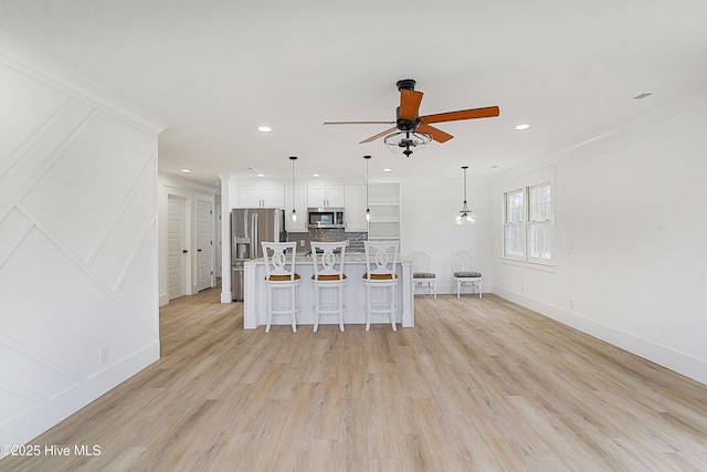 kitchen with stainless steel appliances, white cabinetry, a center island, a kitchen bar, and decorative light fixtures