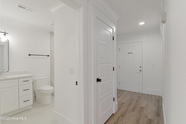 hallway with light wood finished floors, recessed lighting, visible vents, and baseboards