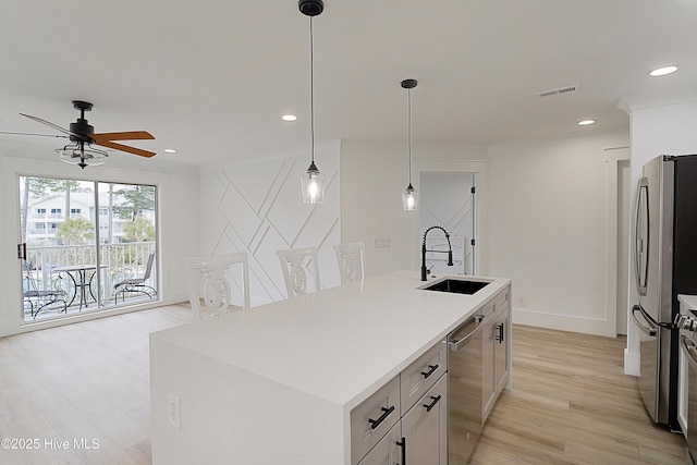 kitchen with light countertops, visible vents, appliances with stainless steel finishes, a kitchen island, and a sink