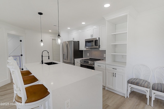 kitchen with stainless steel appliances, light countertops, an island with sink, and open shelves