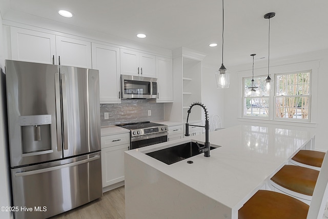 kitchen featuring stainless steel appliances, a sink, an island with sink, and open shelves