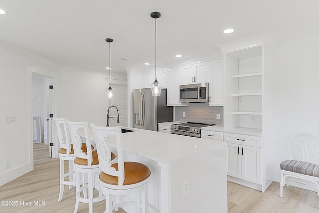 kitchen with an island with sink, hanging light fixtures, stainless steel appliances, light countertops, and open shelves