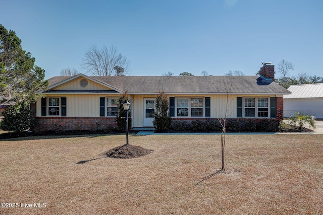 ranch-style house featuring brick siding, a chimney, and a front lawn